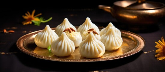 Delicious Coconut Khoya Modak on a Traditional Plate Garnished with Almonds and Greenery in Selective Focus