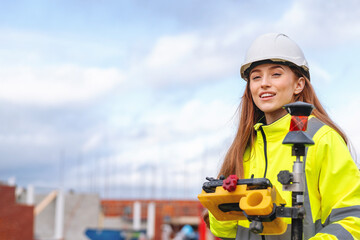 Woman builder using surveying equipment on site under a cloudy sky