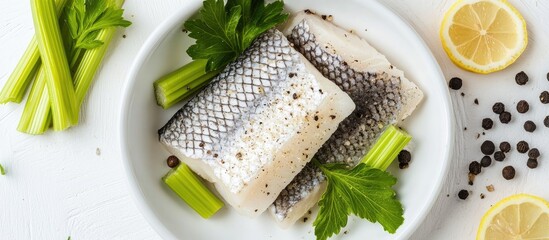 Sea bass fillets seasoned with lemon salt garnished with black pepper and vibrant celery leaves on a clean white background