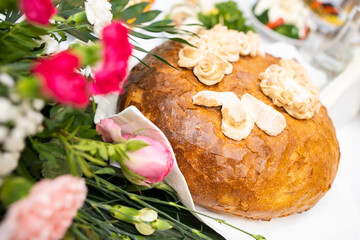 Traditional wedding bread decorated with symbolic ornaments and surrounded by fresh flowers. A cultural centerpiece representing unity, prosperity, and hospitality during festive celebrations.