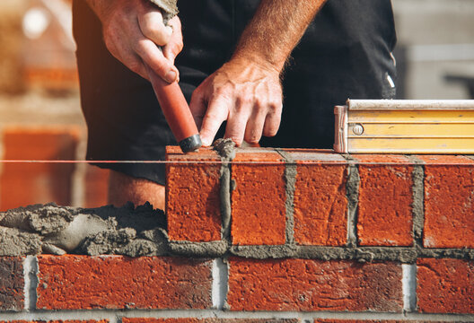 Skilled masonry work in progress during daylight at a construction site with bricks and mortar