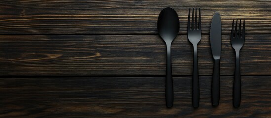 Multifunctional black utensils arranged on a rustic wooden table with ample copy space for food related advertisements or promotions