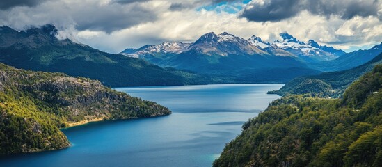 Obraz premium Scenic mountain lake landscape with lush greenery and dramatic cloud formations reflecting vibrant blue hues in a serene natural setting