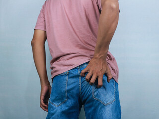Man in jeans scratching hand his itchy ass