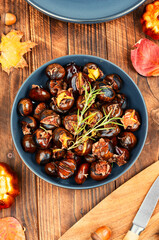 Cracked roasted chestnuts on rustic wooden table.