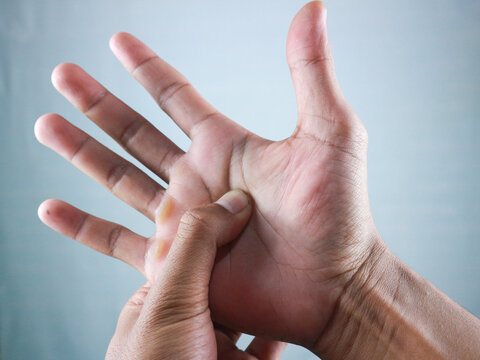 man's hand pressing acupressure point on the hand that feels pain and pain from work.
