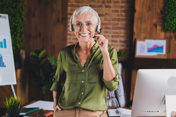 Portrait of aged corporate woman touch headset microphone wear shirt modern loft interior business center office indoors