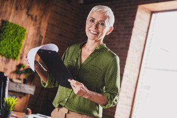 Photo of charming lady hr recruiter dressed shirt eyewear hold cv resume document workplace workstation loft interior indoors