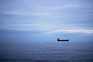 Naklejka premium A view of the vast sea and sky, with a distant ship sailing in the horizon