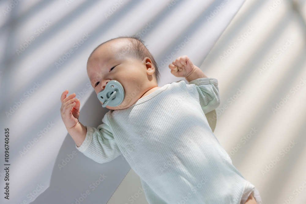 Wall mural Asian newborn baby with pacifier and lying on the mat