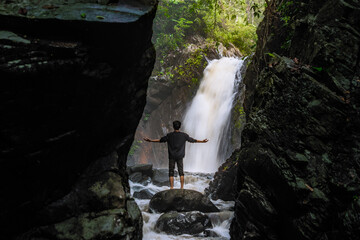 Man standing in front of beautiful Waterfall. Beautiful landscape with waterfall and cliff scenery