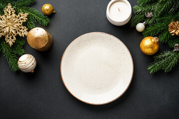 Christmas food background. Craft plate with golden christmas decorations at black. Flat lay with copy space.