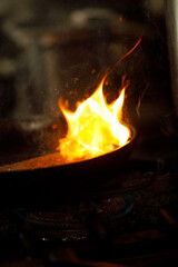 Fire is coming from a saucepan in the stove