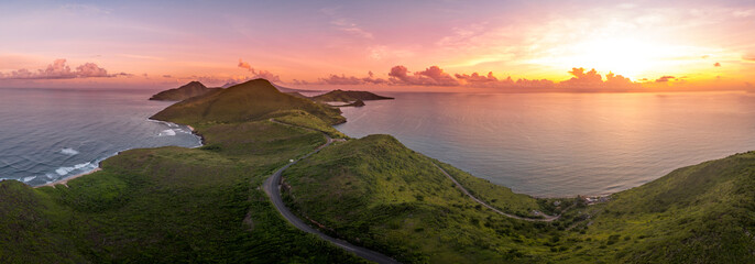 Dramatic sunset over St Kitts, Basseterre, South Friars Bay colorful sun rays painting the clouds pink, red and purple as the sun sets over the Caribbean sea 