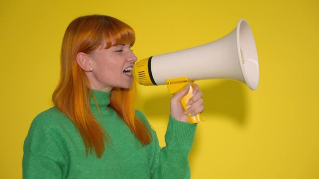 Woman in green sweater shouting into a megaphone against bright yellow background
