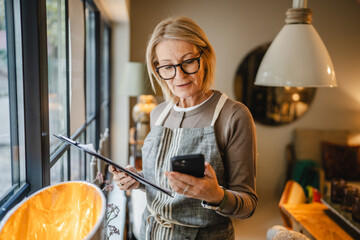 woman entrepreneur work on clipboard and mobile phone at sales shop