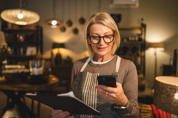 woman entrepreneur work on clipboard and mobile phone at sales shop