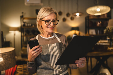 woman entrepreneur work on clipboard and mobile phone at sales shop