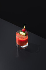 Cóctel Bloody Mary adornado con tomate cherry y pepino sobre fondo negro