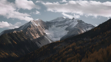 Obraz premium A mountain range with snow-capped peaks and autumn-colored trees below