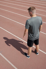 Fototapeta premium Individual jogging on track with focus on shadow cast on surface creating interesting visual element highlighting movement and perspective