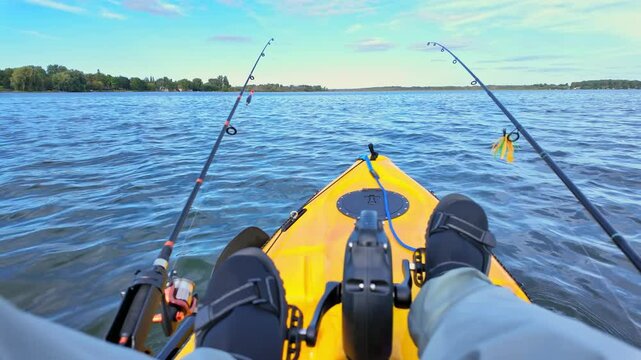 Angler POV at the lake during fishing in Fishing pedal kayak. Rafting in calm lake waters and enjoying peaceful landscapes. Active weekend in the wild lake pond. Bass and pike fishing.