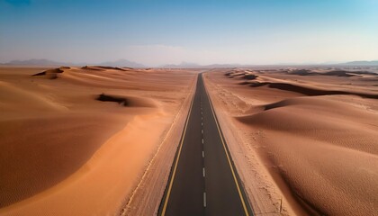Fototapeta premium Aerial view of a long, straight, empty road in the middle of the desert: an asphalt highway stretching between sand dunes in a desert environment near Riyadh, Saudi Arabia.