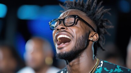 A man with glasses wearing a patterned shirt erupts into genuine laughter, basking in excitement and joy surrounded by a lively atmosphere representing unfiltered happiness.