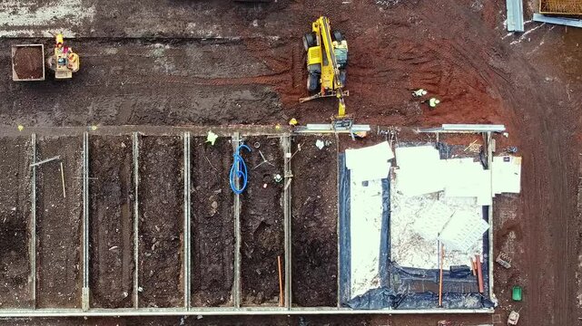 Construction process of a new building site showing equipment and workers at a residential development area