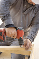 Carpenter working on wooden board using professional electric cordless screwdriver