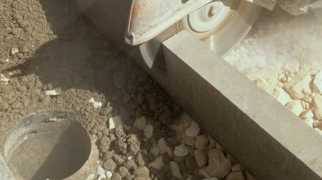 Cutting concrete with a petrol saw and dimond blade at a construction site in bright daylight