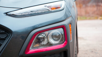 headlight of modern prestigious car closeup. beautiful headlights of a car. dark gray color, red...