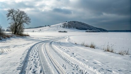 A frozen landscape with deep tire tracks and a snow-covered hill in the background, snowy, vast, winter wonderland