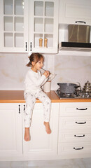 Little chef is sitting on the kitchen table and cooking dinner . High quality photo