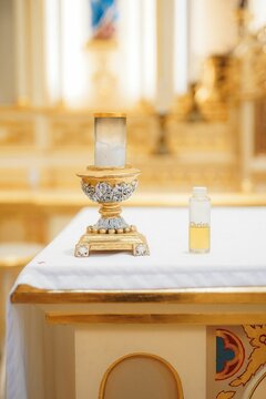 Close-up of a religious altar with a candle and a bottle of chrism oil in a church
