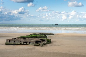 Remains of a World War II Mulberry harbor on a sandy beach at Arromanches, Normandy, France