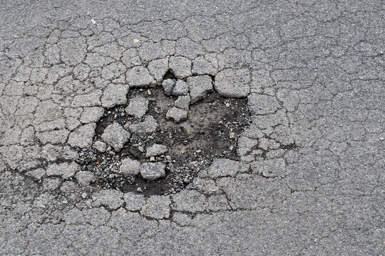 large hole on asphalt road, highway with dirt mud pothole and fracture, damage textured tarmac road, transportation background