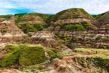 A mountain range with a green hillside and a person walking on the side