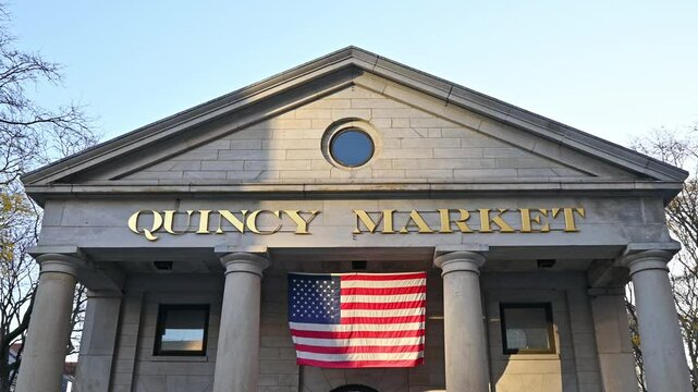 The iconic architecture of Boston in Massachusetts with the famous Quincy Market building and an American flag on a sunny morning.