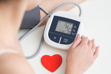 Woman measuring blood pressure at home with electronic equipment. Low blood pressure background. Prevention of cardiac diseases and heart attacks. Health checkup. Heart care diagnosis.