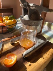 Vintage Citrus Juicer with Fresh Orange Juice in Sunlit Kitchen, Featuring a Rustic Cutting Board...