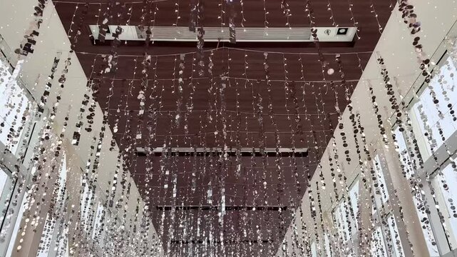 4K footage of christmas decoration, trees, tinsels, slingers hanging from ceiling. Walking through christmas decoration to celebrate seasons greetings, seen the white themed leaves, trees, and silver 