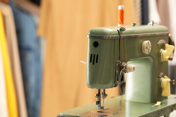 Vintage sewing machine with thread on blurred background, closeup. Space for text