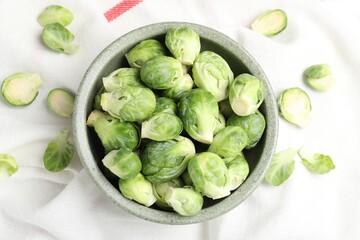 Fresh Brussels sprouts in bowl on white table, top view