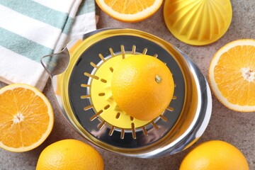 Juicer and oranges on grey table, top view