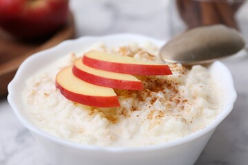 Delicious rice pudding with cinnamon and apple on table, closeup