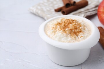 Delicious rice pudding with cinnamon on white textured table, closeup. Space for text