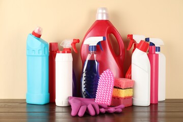 Different cleaning products and supplies on wooden table against beige background