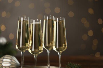 Champagne in glasses on dark background blurred Christmas lights, closeup. Bokeh effect