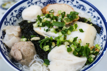 close up of Hong Kong style fish soup rice noodles with beef balls, fish balls, fish slice and seaweed. Spring onion on top